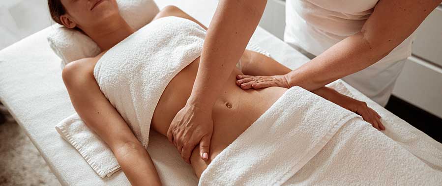 Massaggio addome in spa, mani del terapista che stimolano rilassamento e benessere digestivo