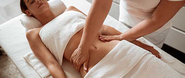 Massaggio addome in spa, mani del terapista che stimolano rilassamento e benessere digestivo