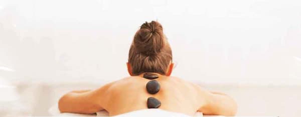 una donna si rilassa con le pietre dell'hot stone massage sulla schiena