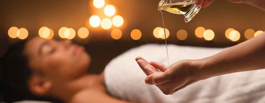 Massaggio rilassante con oli essenziali in una spa, mani del terapista che versano olio caldo in un ambiente con luce soffusa e atmosfera rigenerante