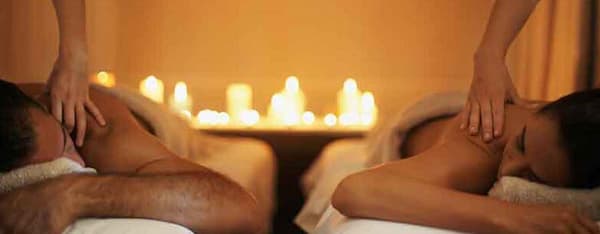 due operatrici che massaggiano una coppia sdraiata a lume di candela
