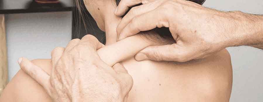 mani di terapista che effettua un massaggio connettivale sulla schiena di una donna seduta