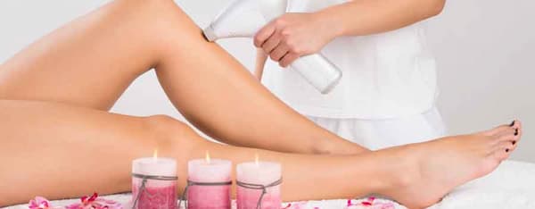 operatrice che esegue l'epilazione laser sulla gamba di una donna
